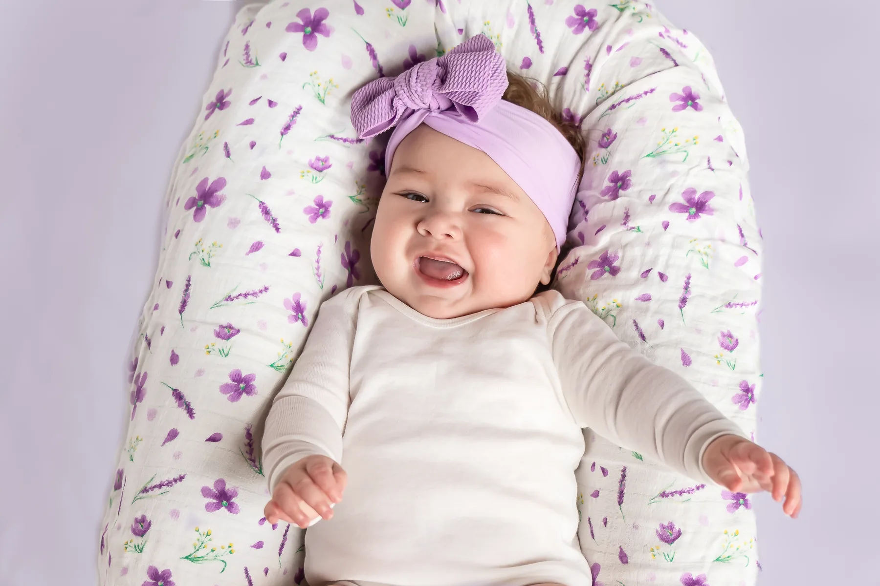 Baby smiling on purple floral swaddle