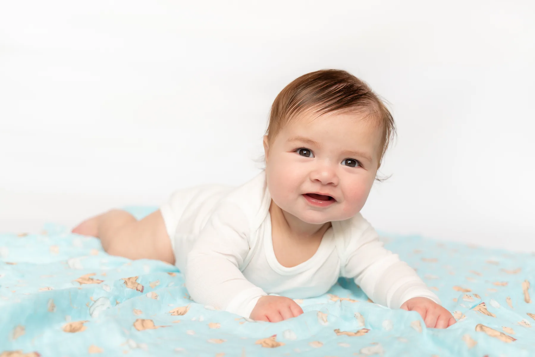 Baby smiling on blue patterned swaddle